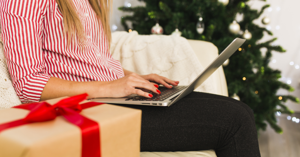 secretaresse op laptop met geschenk cadeau kerstboom